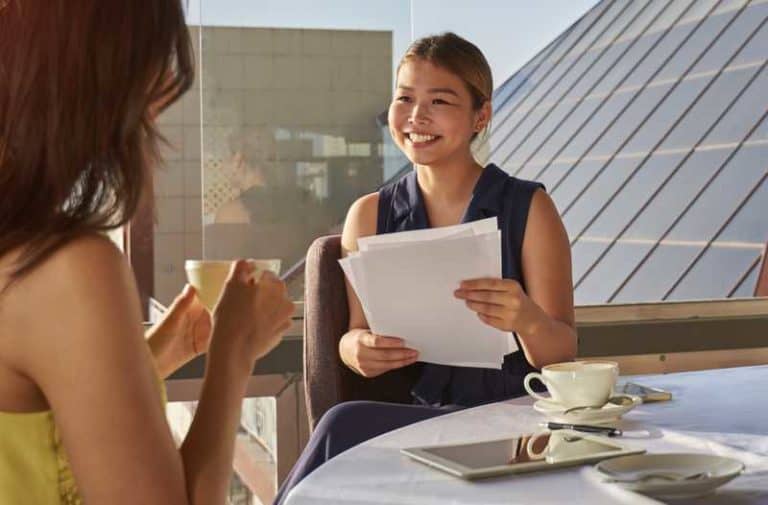 Personen zitten aan een tafel met een tablet, smartphones en gekleurd papier