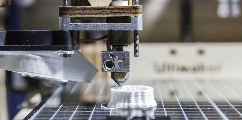 Een 3D-printer print een wit plastic object bestaande uit laagjes