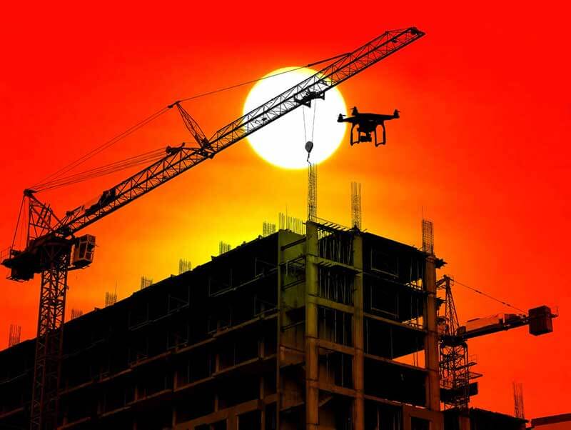 Boven een bouwsite bij zonsondergangunset zweeft een drone boven een bouwconstructie