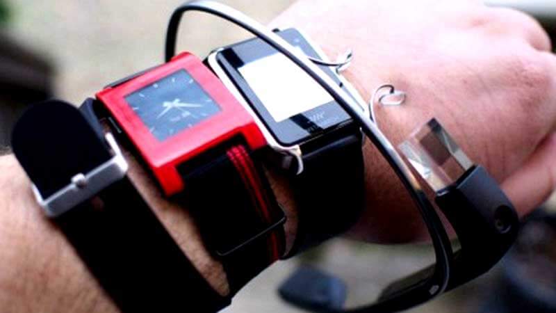 Een arm met drie smartwatches en futuristische AR-bril om de pols