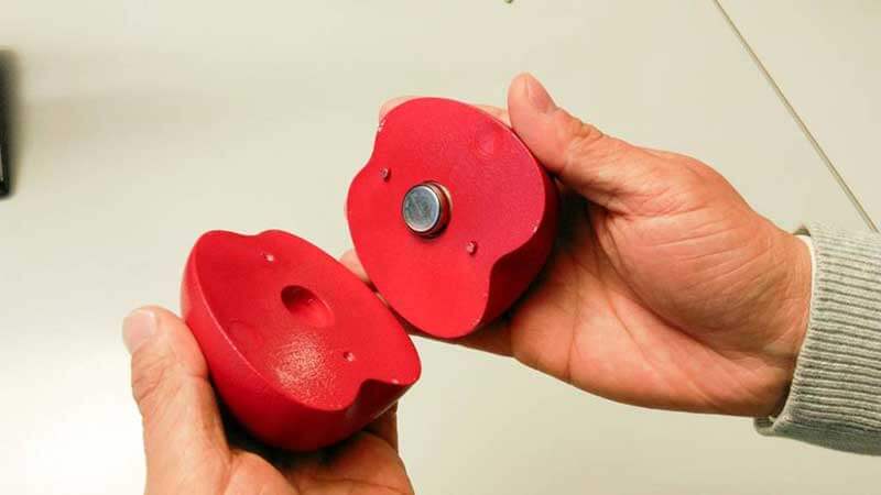 Handen met twee helften van een 3D-geprinte appel, ontwikkeld door Empa-onderzoekers