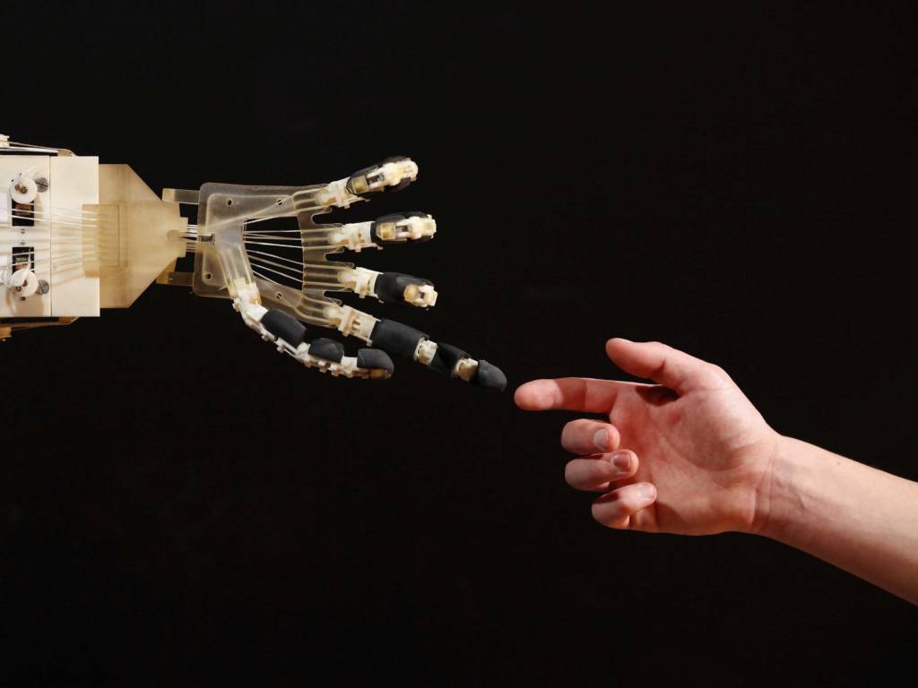 Robothand raakt een menselijke hand aan tegen een zwarte achtergrond
