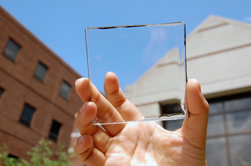 Close-up van een hand die een transparant vierkant stuk glas vasthoudt