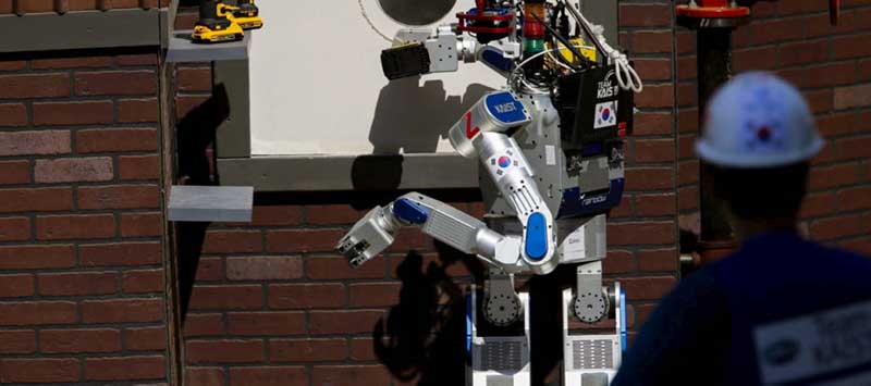 Een humanoïde robot staat voor een muur van bakstenen