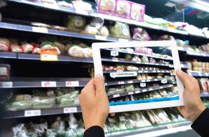 Twee handen houden een tablet vast waarop supermarktartikelen afgebeeld staan||||