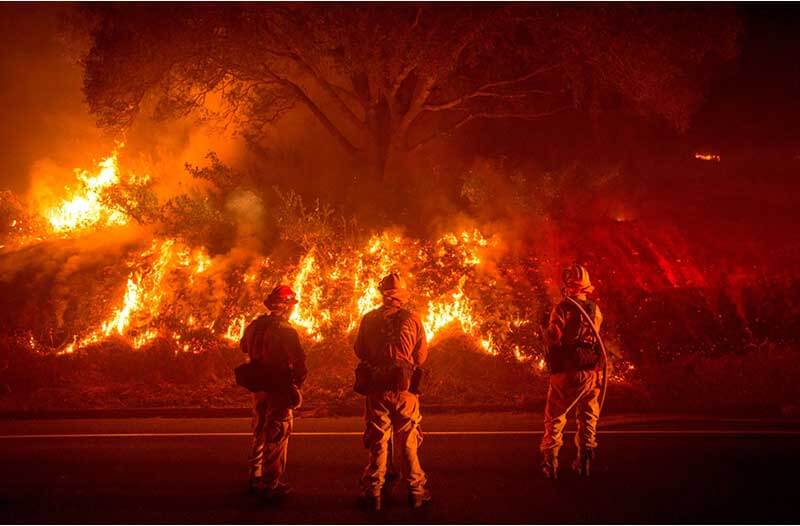 Drie brandweermannen blussen bosbrand