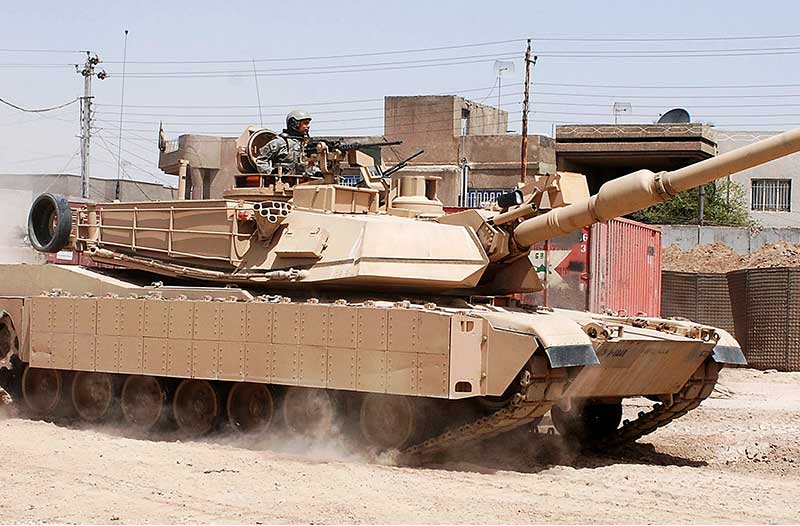 Een tank rijdt op een zandweg in een oorlogsgebied