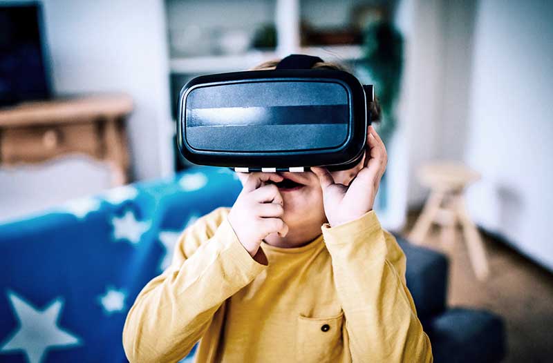 Kind met geel shirt zit in een kamer met een VR-headset op