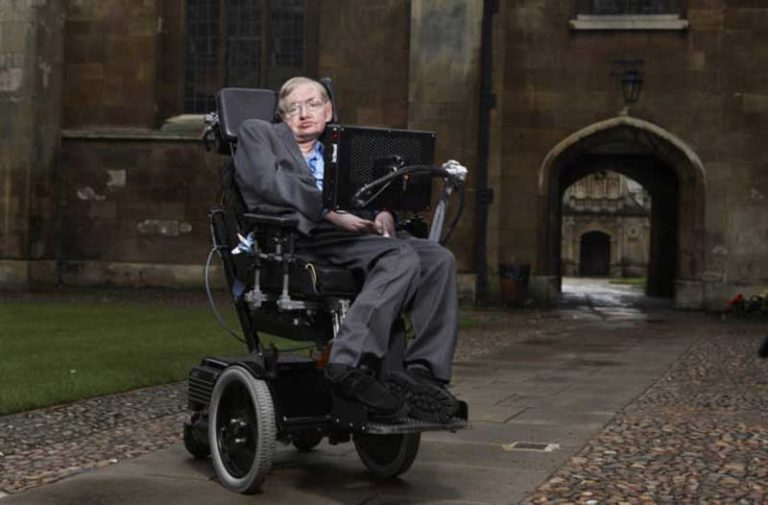 Natuurkundige Stephen Hawking zit in zijn rolstoel voor een oud gebouw
