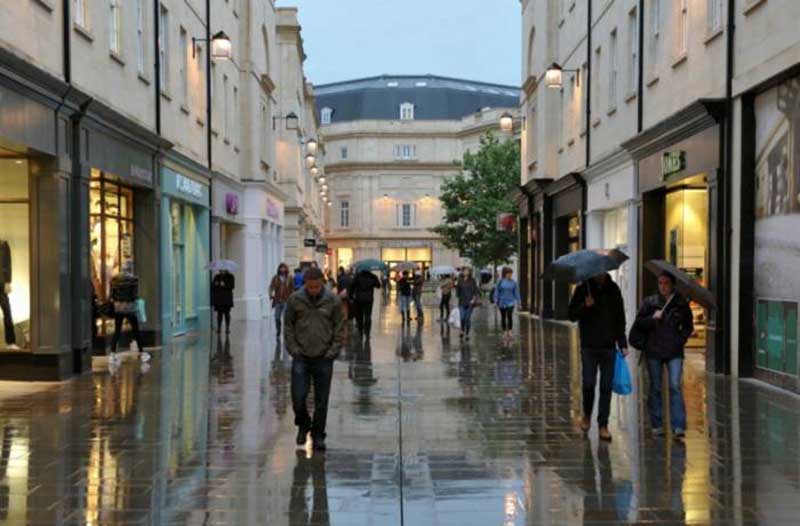People walking through shopping street in the rain