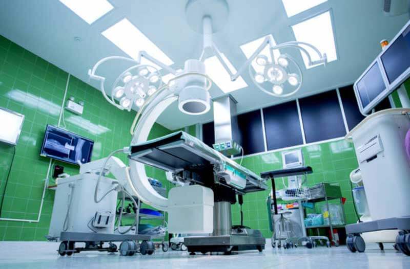 A surgical room with green walls and a lot of equipment