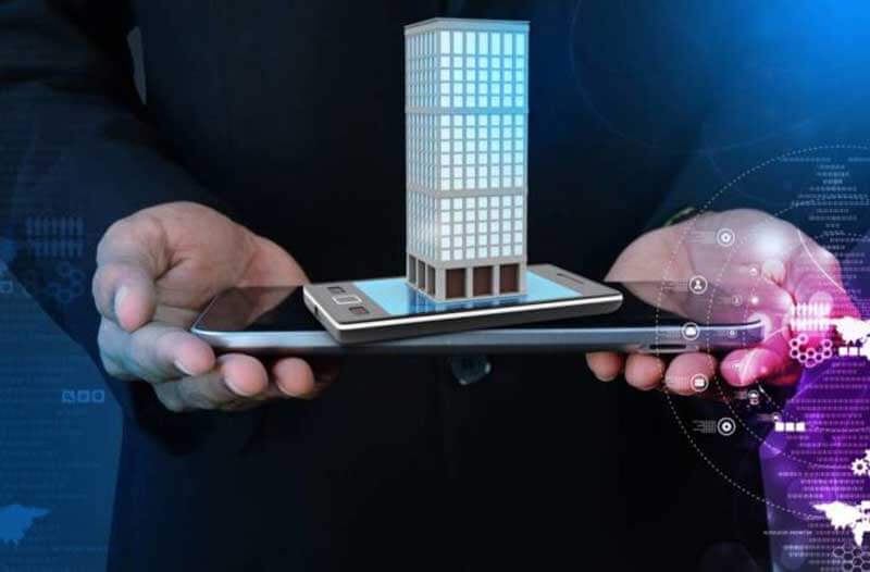 Person holding a tablet and a smartphone which is projecting a holographic image of a building