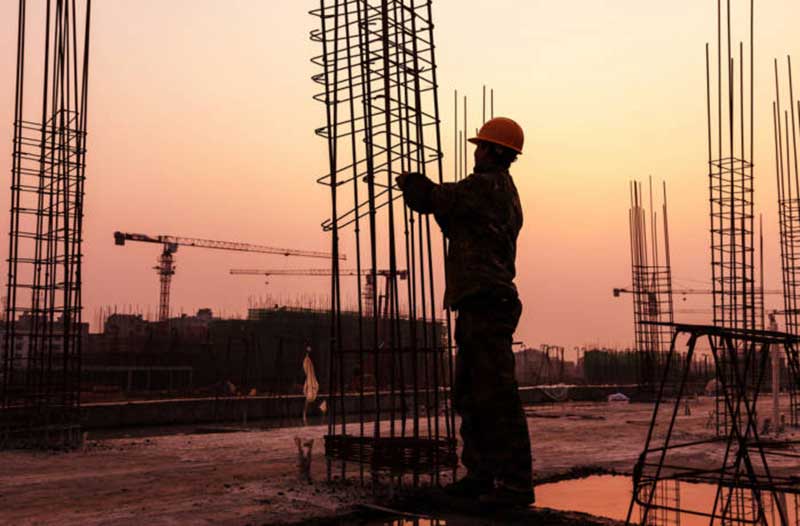 Construction worker working on a reinforced steel structure at sunset