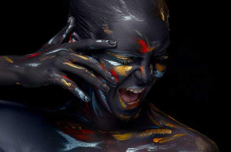 Woman painted with black, red, yellow and blue colours