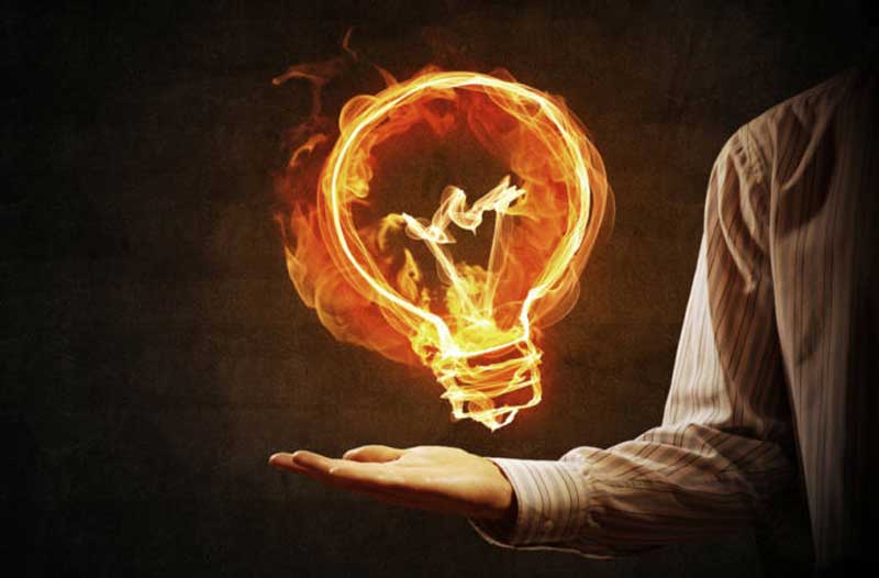 flaming light bulb floating above man’s hand