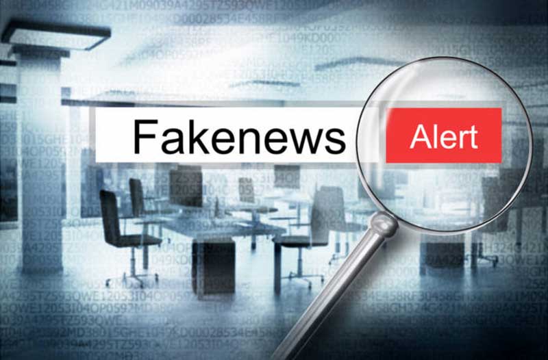office with Fakenews Alert written in the foreground and a magnifying glass on the word Alert