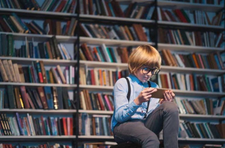 Kind zit in een bibliotheek en kijkt naar smartphone