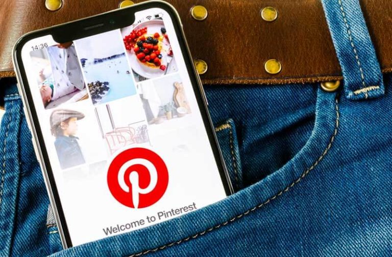 Een smartphone met Pinterest op het scherm steekt uit de zak van een spijkerbroek