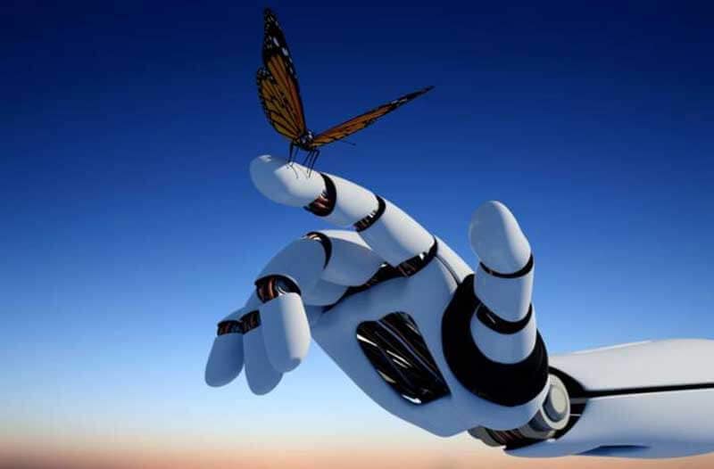 Colorful butterfly standing on a robotic finger with the sky in the background