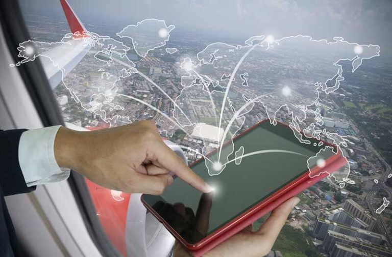 Een man in een vliegtuig boven een stad houdt een tablet uit het raam met daarboven een digitale wereldkaart