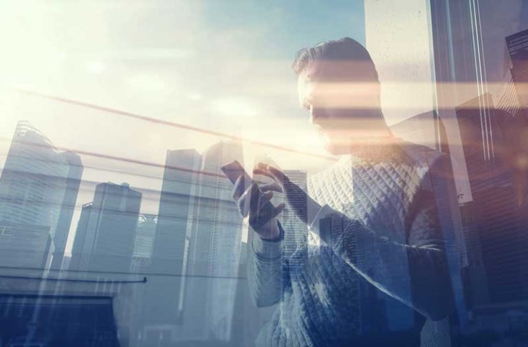 Reflectie van een man met een smartphone met wolkenkrabbers op de achtergrond