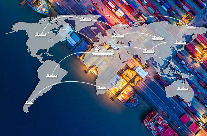 Aerial image of a shipping port at night with a digital overlay of the world map