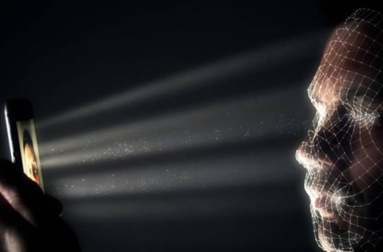 Persoon in een donkere ruimte houdt een smartphone vast die lijnen en stippen op zijn gezicht projecteert