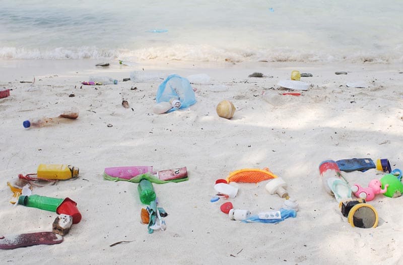 White sandy beach with plastic litter forming the word STOP