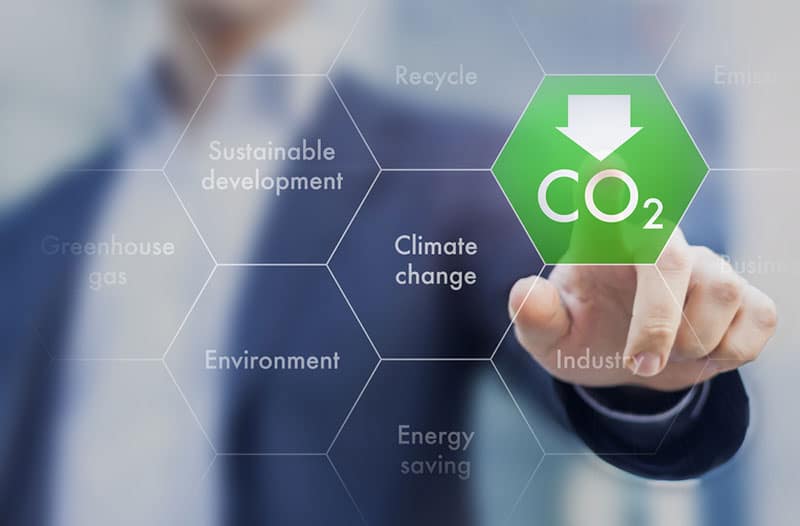 Een transparant zeshoekig raster met een wazig beeld van een persoon op de achtergrond. Elk veld in het raster bevat teksten over klimaatverandering en CO2 is in groen gemarkeerd.