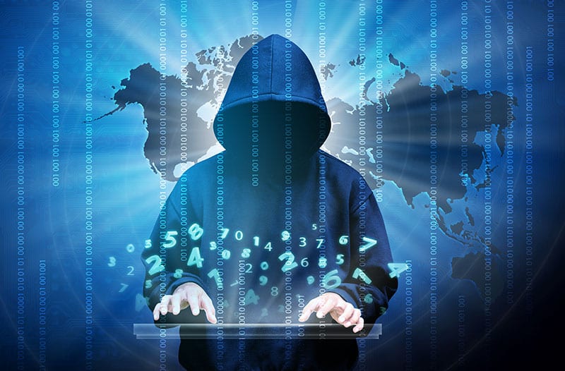 Persoon met hoodie op zit voor een scherm met een wereldkaart op een toetsenbord te typen waarboven digitale nummers zweven