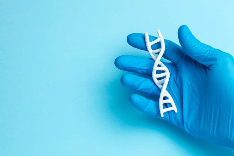 Hand in blauwe handschoen houdt een DNA-streng vast