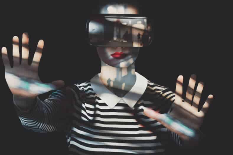 Woman with a striped shirt and stretched-out hands wearing a VR headset