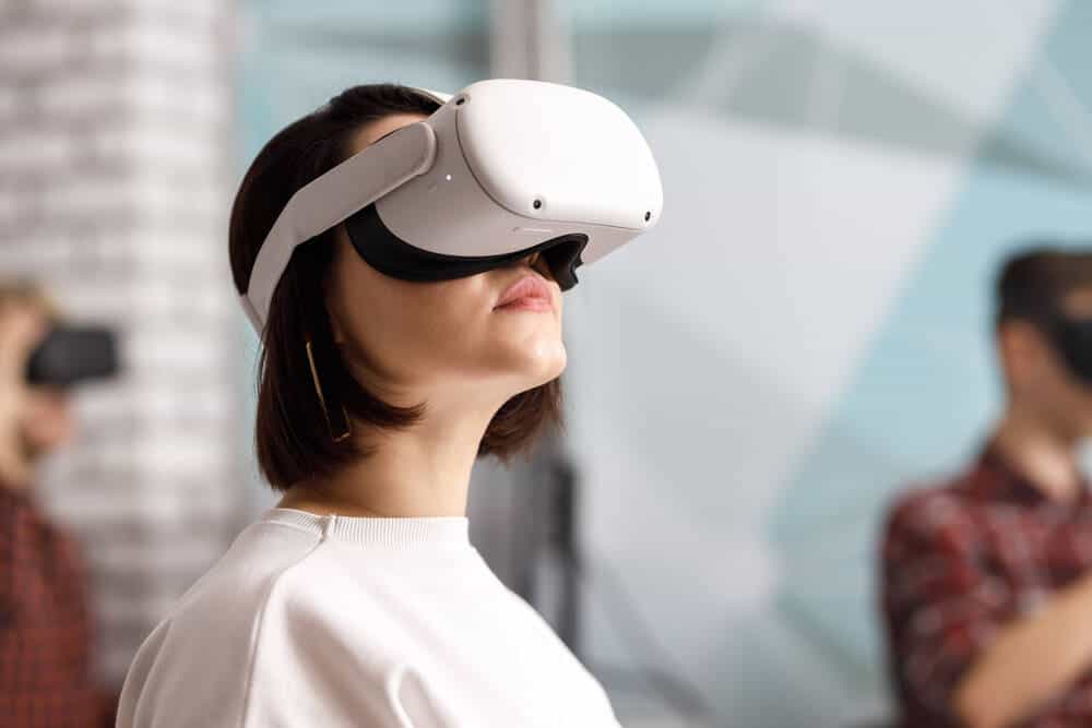 Vrouw met witte kleding en donker haar draagt een witte VR-bril op haar gezicht