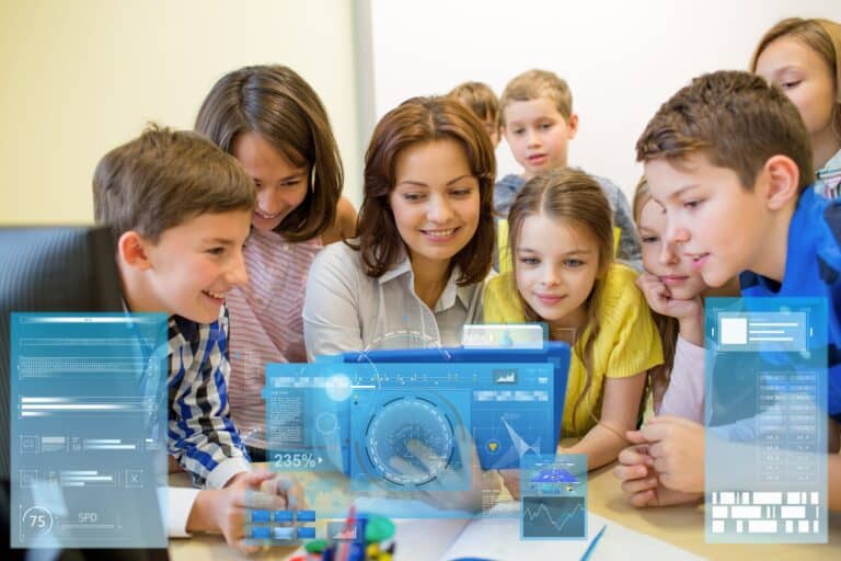In een klaslokaal zitten jonge kinderen achter hun bureaus en staat een witte kunststof robotleraar voor het krijtbord.