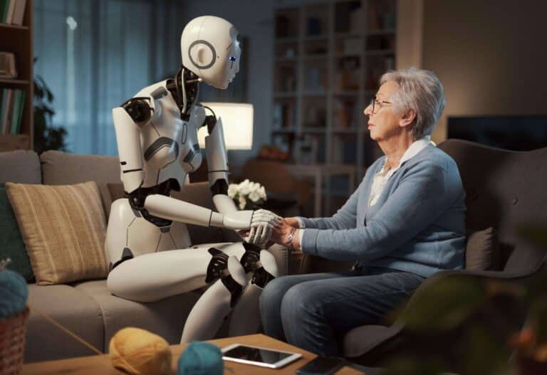 Moment van verbinding: een robot en een oudere vrouw zitten op een bank en houden elkaars handen vast.