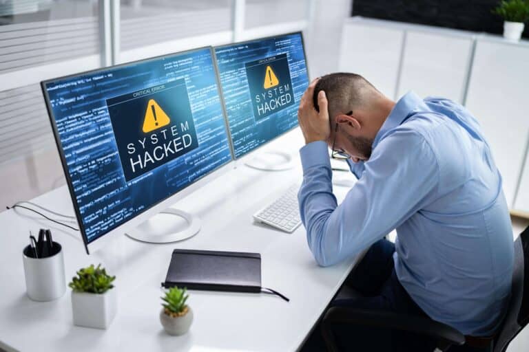 Een gestresste man op kantoor ontdekt dat zijn computersysteem gehackt is.