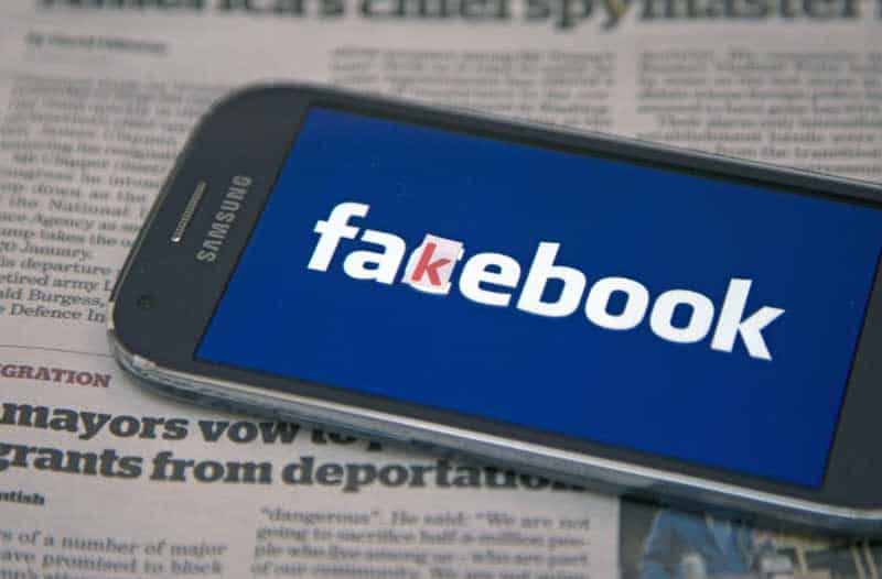 Cell phone with Facebook on top of newspaper with fake news