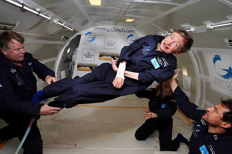 Two men and a woman holding Stephen Hawking who’s floating in a Zero G plane