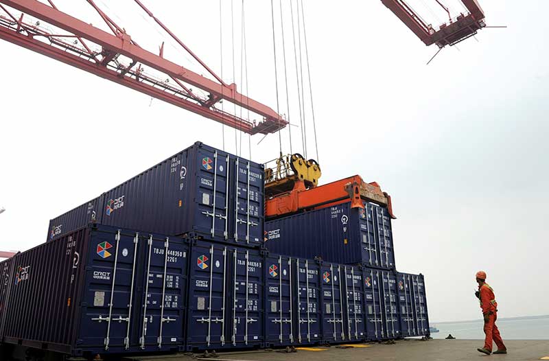 Shipping port with black shipping containers and a crane