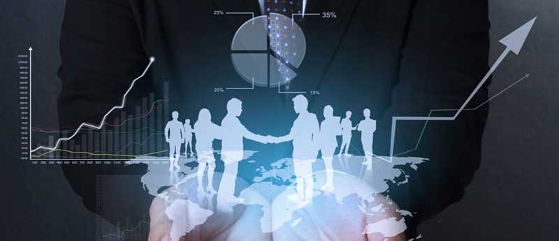  Hands with a holographic image of silhouettes of people shaking hands and standing on a world map