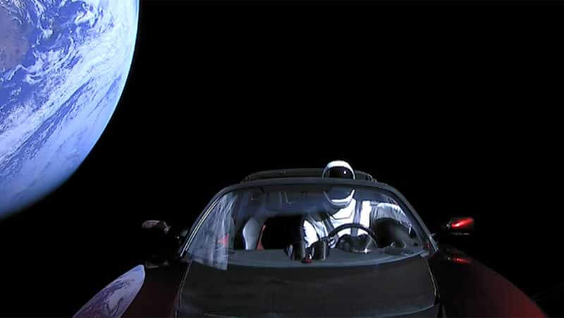 A car with a dummy driver in a space suit flying away from Earth