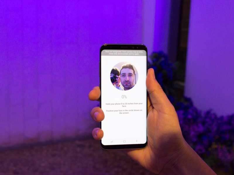  A man holding a Samsung Galaxy S8, showing the facial recognition system on the display