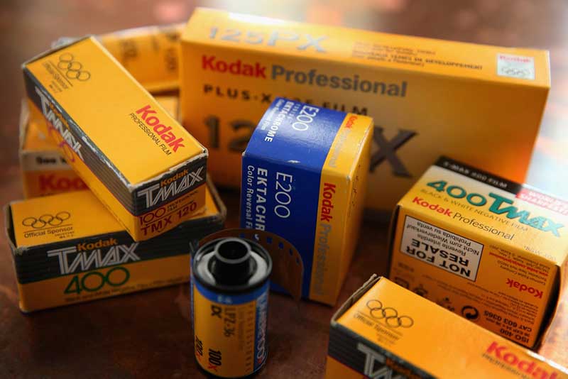 Eight yellow Kodak film roll boxes, with a roll of film next to them