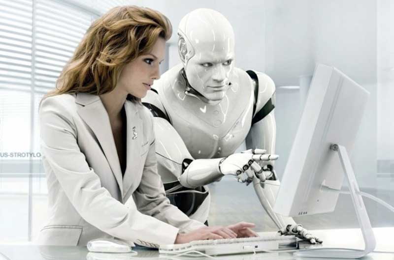 White robot and woman in white suit looking at computer screen