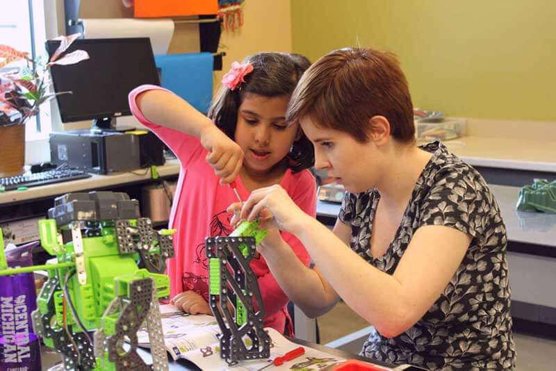 Child and teacher building mechanical toys