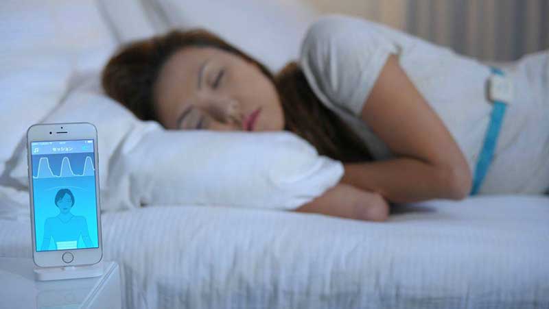 Woman sleeping with a smartphone on the nightstand in front of her coaching her sleep