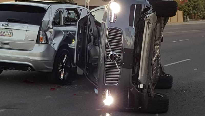 Car accident showing a vehicle flipped on its side leaning on a damaged car next to it