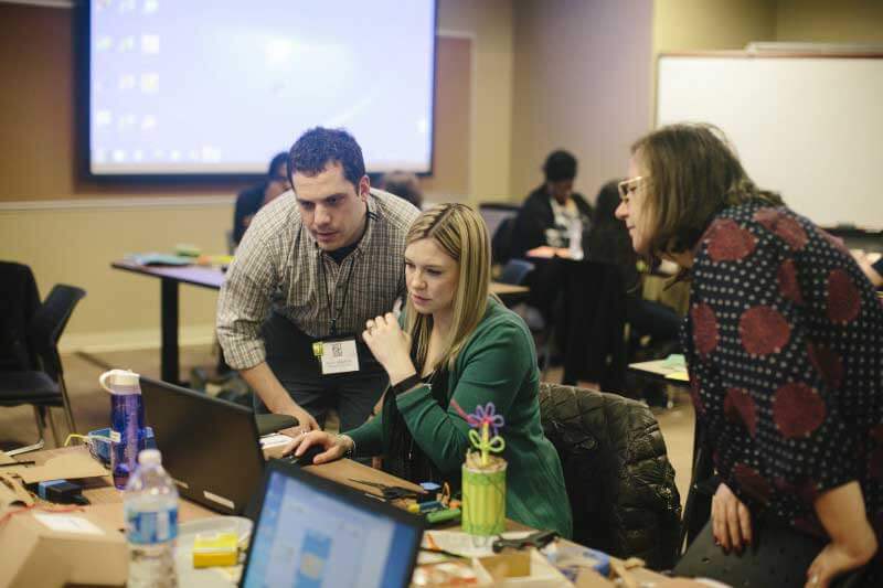 Man and two women at desk in classroom 