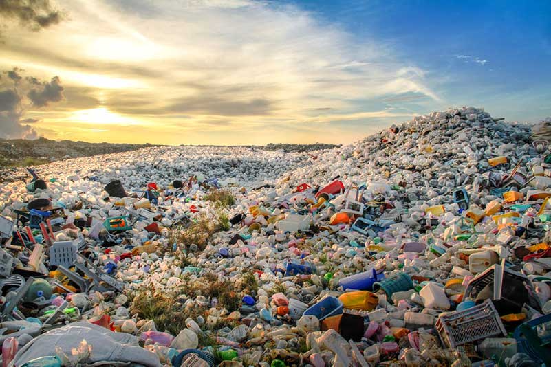 A landfill full of plastic garbage with a sunny sky in the background