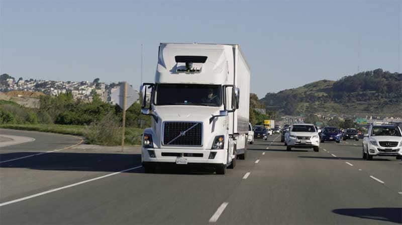 A white Volvo self-driving truck cruising down the highway